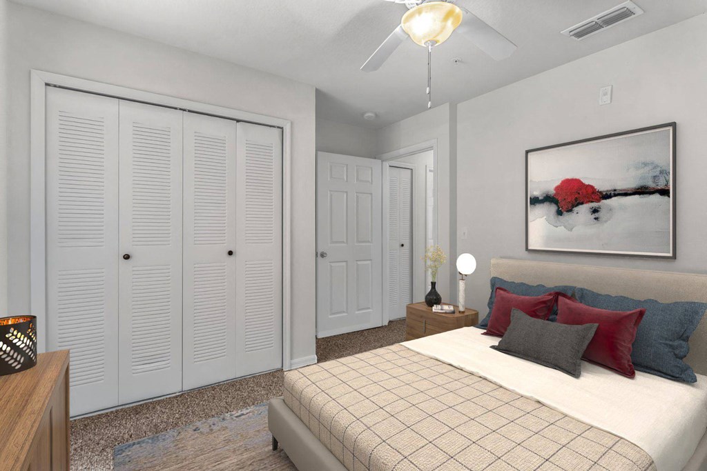 A bedroom with a bed, a nightstand, and a painting on the wall at The Villages on Millenia Apartments, Orlando, FL, 32839