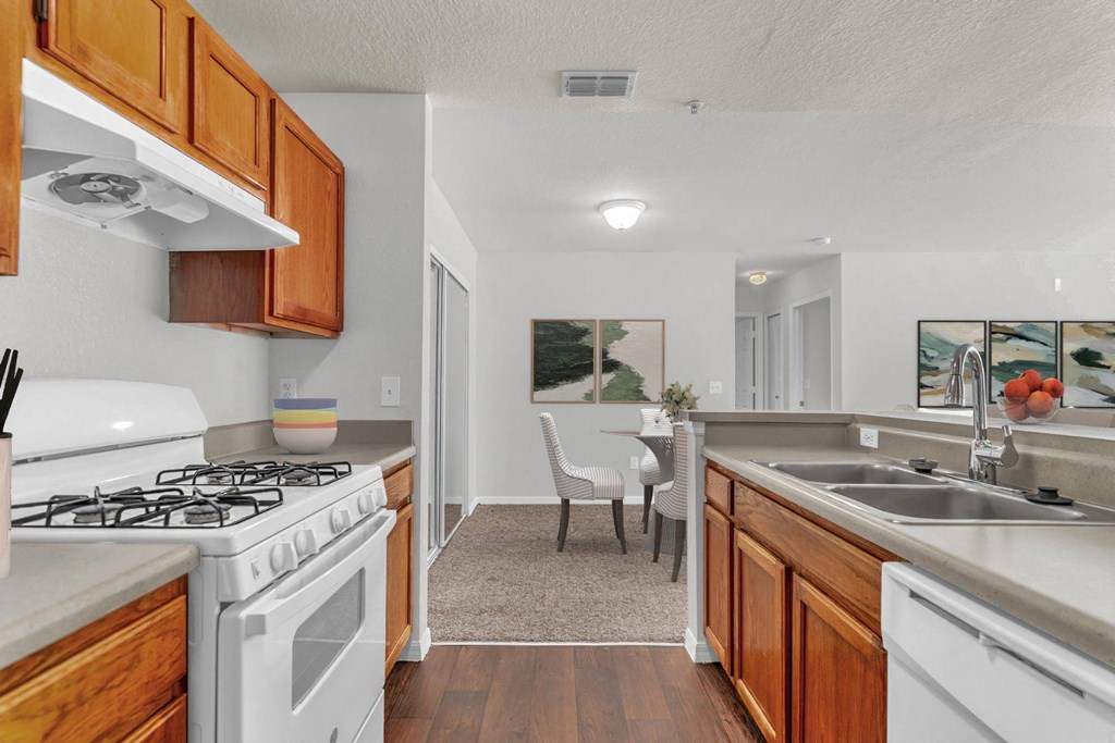 A kitchen with a white stove top oven and a white gas stove at The Villages on Millenia Apartments, Orlando, FL