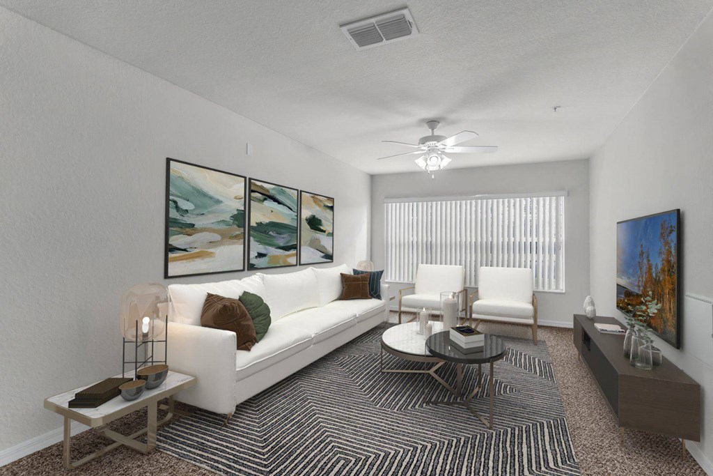 A living room with a white couch, a coffee table, and a painting on the wall at The Villages on Millenia Apartments, Orlando, Florida