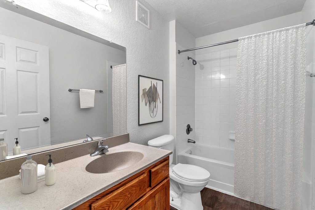 A bathroom with a white toilet, sink, and shower curtain at The Villages on Millenia Apartments, Florida, 32839