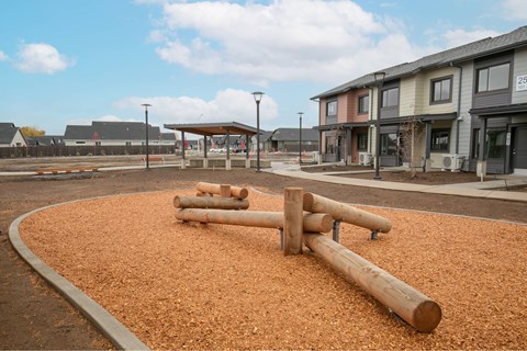 A playground with a brown sandbox and wooden logs.