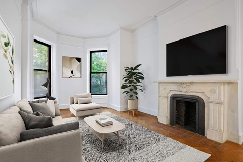 A living room with a grey couch, a coffee table, a fireplace, and a large TV mounted on the wall.