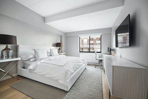 A bedroom with a large bed and a television on the wall.