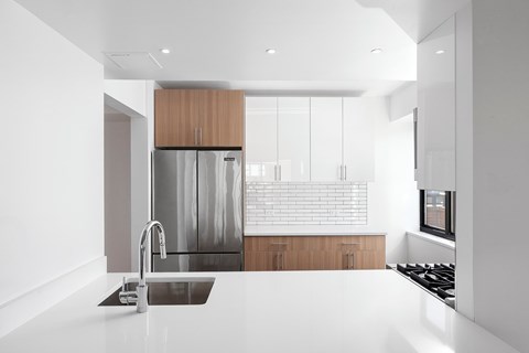 A modern kitchen with a stainless steel refrigerator and a white countertop.