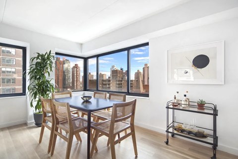 A dining room with a table and chairs and a view of the city.