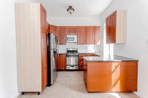 A kitchen with wooden cabinets and a stainless steel refrigerator.