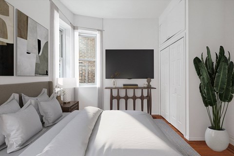 A bedroom with a large bed and a potted plant.