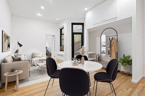 A modern dining room with a white table and black chairs.