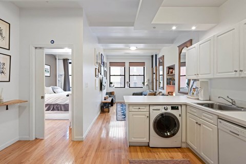 A modern kitchen with white cabinets and a washing machine in the middle.
