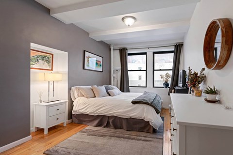 A bedroom with a bed, nightstand, and a window with curtains.