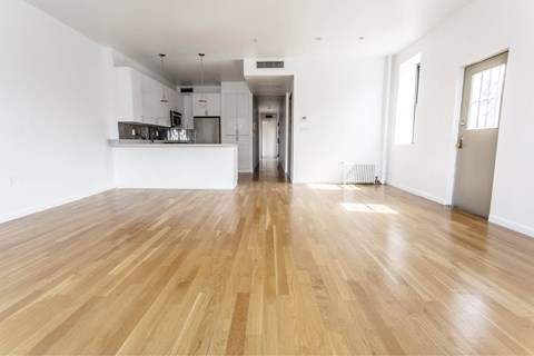 A spacious room with wooden flooring and white walls.