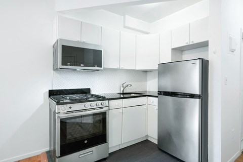 A kitchen with a stainless steel refrigerator, oven, and microwave.