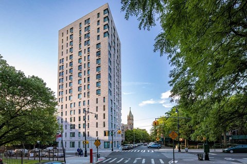 A tall building with many windows is surrounded by trees.