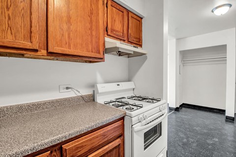 A kitchen with a white stove and wooden cabinets.