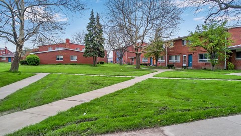 A row of red brick houses with green lawns in front.