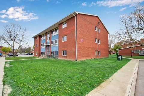 A red brick building with a green lawn in front.