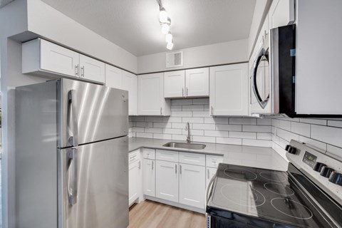 A modern kitchen with white cabinets and stainless steel appliances.