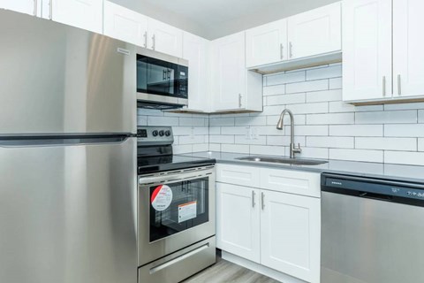 A modern kitchen with a stainless steel refrigerator, oven, and dishwasher.