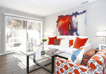 A living room with a white couch and a large abstract painting on the wall.
