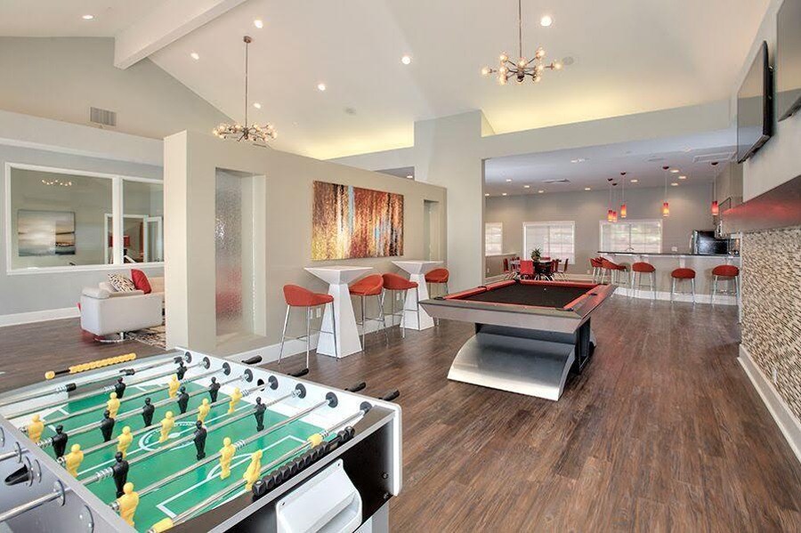 A foosball table is in the middle of a room with a couch and chairs at Kirker Creek Apartments, Pittsburg, CA