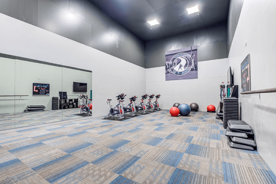 A gym with exercise equipment and a blue carpet at Kirker Creek Apartments, Pittsburg, California
