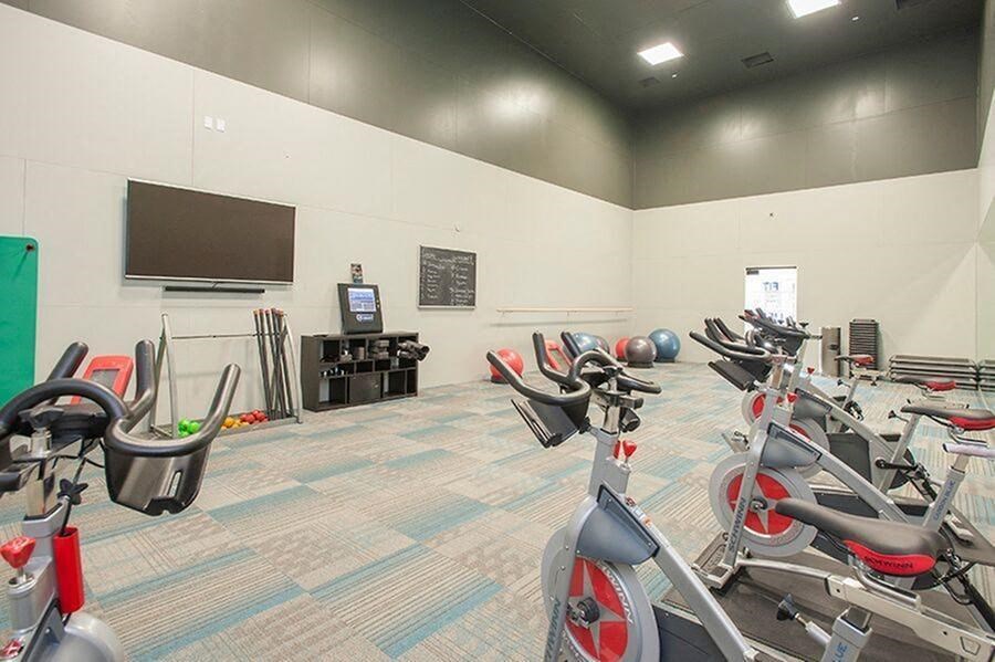 A gym with exercise bikes and a television on the wall. at Kirker Creek Apartments, Pittsburg 94565
