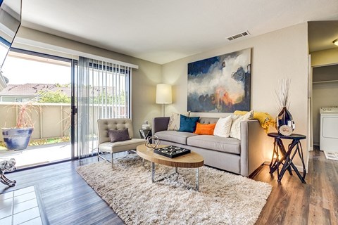 A modern living room with a grey sofa, a coffee table, and a painting on the wall.