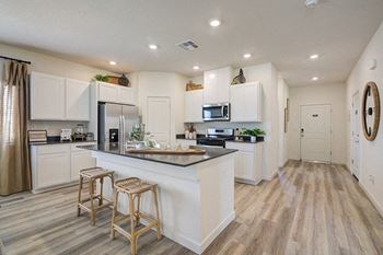 a kitchen with white cabinets and a large island with two stools