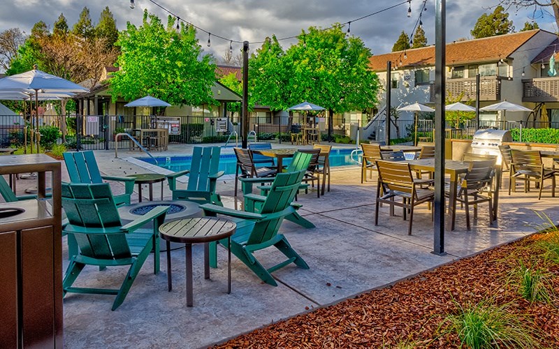 Apartments for Rent in Pleasant Hill - Ellinwood - Seating Area Near Pool, String Lights, and Plants