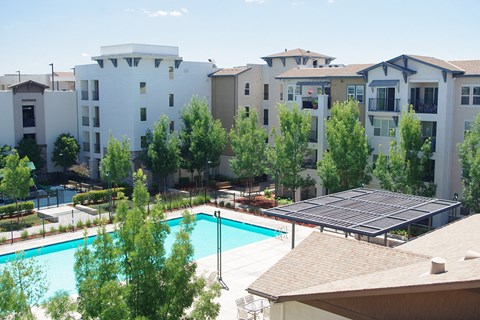 an aerial view of a swimming pool with an apartment building in the background