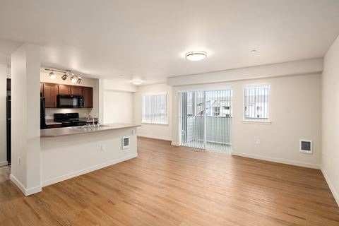 an empty living room and kitchen with wood flooring and a window