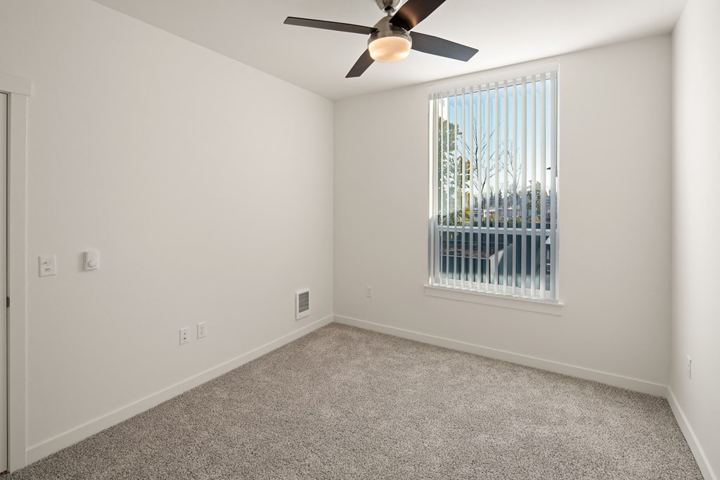 Bedroom with carpet and ceiling fan. Large window.