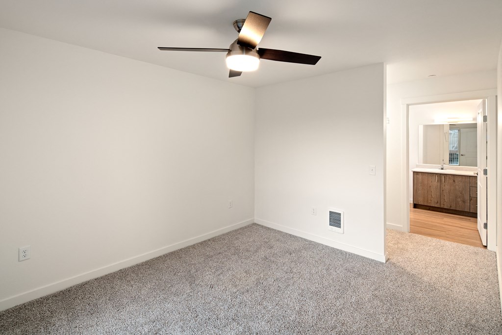 bedroom with ceiling fan, bathroom entrance.