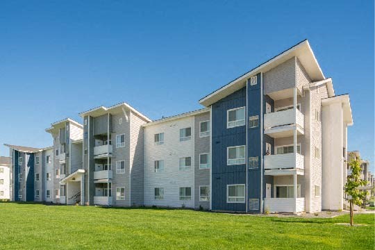 an apartment building with green grass in front of it