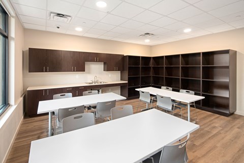 A room with tables and chairs and a kitchenette.