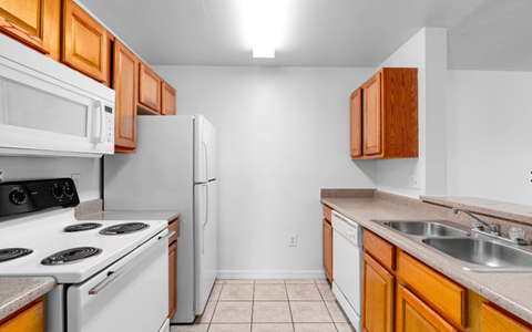 A kitchen with white appliances and wooden cabinets.