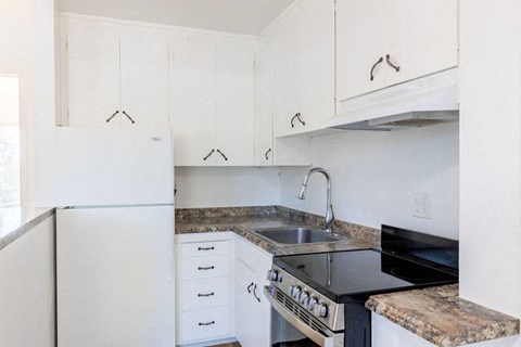 a kitchen with white cabinets and a stove and a sink