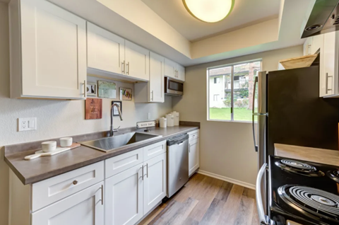 A kitchen with white cabinets and a black refrigerator.