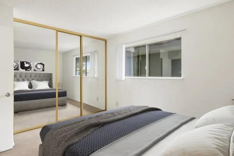 A bedroom with a bed, a mirror, and a window.