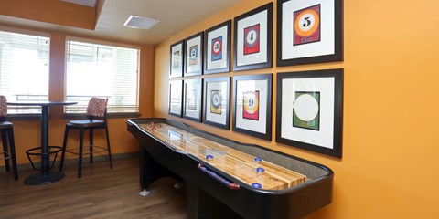 A room with a pool table and framed pictures on the wall.