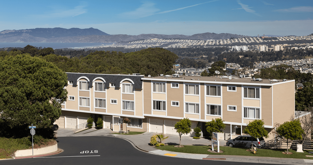 Dale City, CA Apartments-Terrace View-Buidings with garages, paved walkways, greenery, roads, and city views in the background