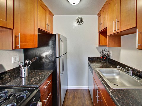 Kitchen with dark wood cabinets and stainless steel appliances at THE POST Apartments, PLEASANT HILL , California