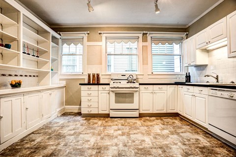 A kitchen with white cabinets and a tiled floor.
