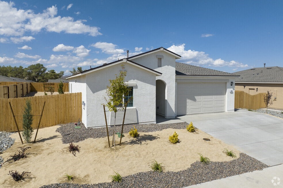 a white house with a yard with sand and a fence