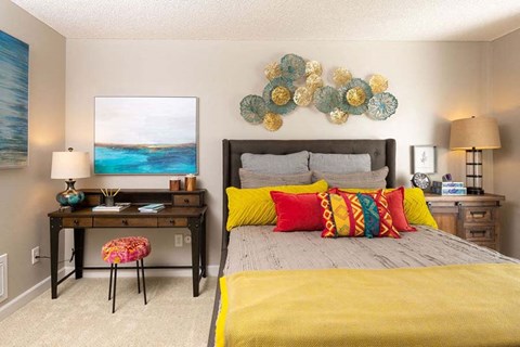 a bedroom with a bed with yellow and red pillows