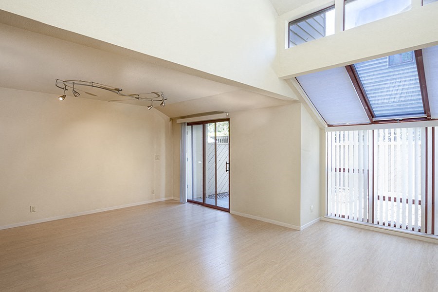 an empty living room with a sliding glass door and a balcony