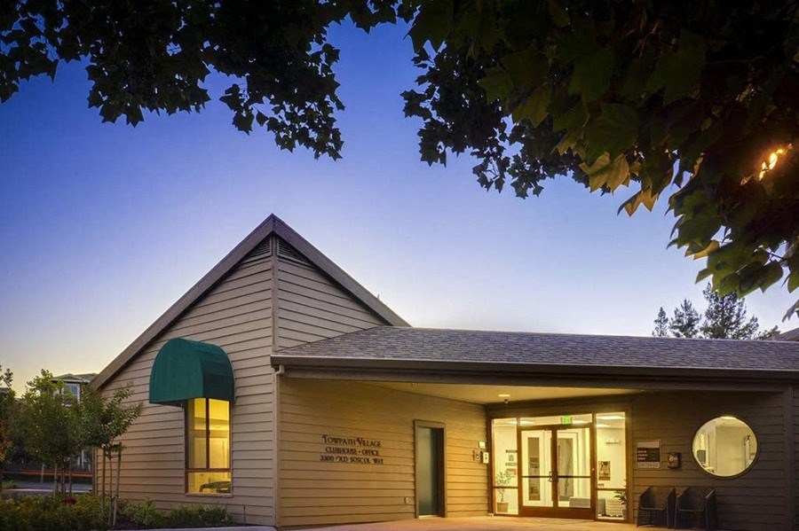Leasing office building with a green awning and a tree in front of it