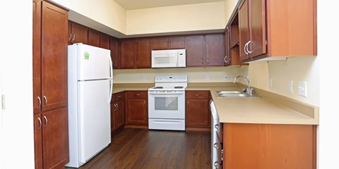 A kitchen with a white refrigerator, white stove, and brown cabinets.