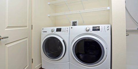 Two white front loading washing machines in a small laundry room.