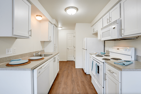 a kitchen with white cabinets and appliances and a white refrigerator